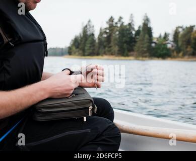 l'homme s'est assis à pêcher à bord d'un bateau tenant son équipement de pêche en mer Banque D'Images