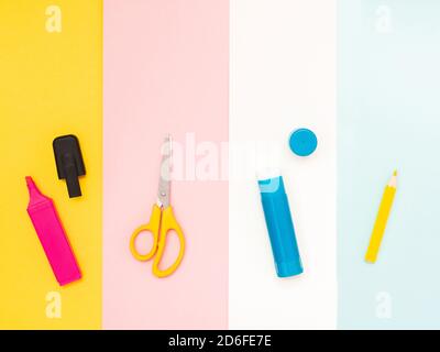 Retour à l'école, concept d'éducation. Outils scolaires multicolores; marqueur rose, ciseaux jaunes; colle bleue; crayons blancs isolés sur le dos de différentes couleurs Banque D'Images