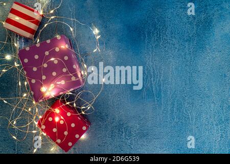 Composition des fêtes de Noël avec boîtes cadeaux de fête et guirlande illuminée en bleu. Fond de Noël avec cadeaux dans un emballage en papier. Station santé Copy Banque D'Images