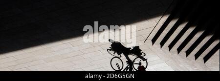 Silhouette abstraite d'ombre d'arrière-plan d'une personne grimpant à vélo à côté des escaliers extérieurs, sépia à contraste élevé noir et blanc Banque D'Images