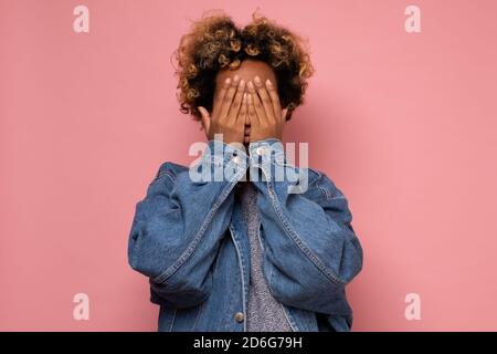 Jeune femme africaine couvrant le visage avec les mains cachant ses émotions à tout le monde. Banque D'Images