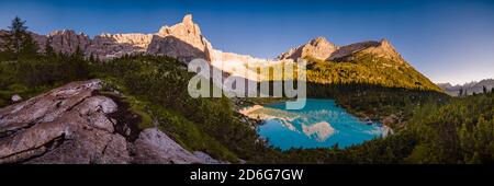 Vue panoramique sur le lac turquoise Lago di Soraapiss, les sommets des montagnes Punta Nera et Cima del Laudo au loin, au lever du soleil. Banque D'Images