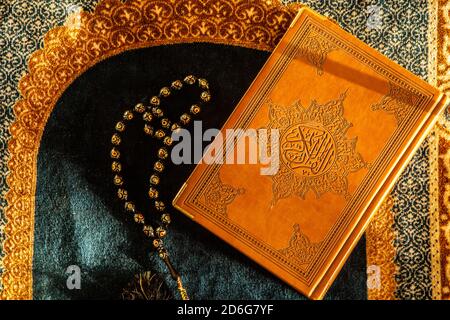 Rosary et Noble Coran sur tapis de prière avec lumière naturelle Banque D'Images