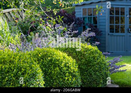 Jardin privé paysagé et ensoleillé (design contemporain, fleurs d'été, plantes frontalières, balles, abri d'été d'angle) - Yorkshire, Angleterre, Royaume-Uni. Banque D'Images