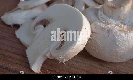 Champignon blanc éclatant et moelleux en gros plan sur une planche à découper en bois. Des détails spectaculaires sont visibles dans cette macro-photo isolée des champignons. Banque D'Images