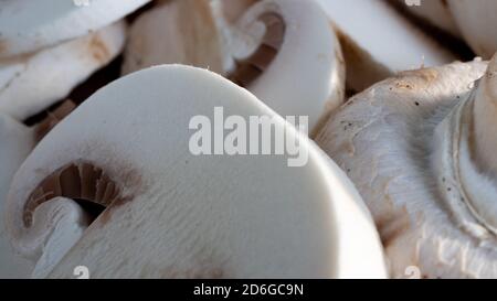 Champignon blanc éclatant et moelleux en gros plan sur une planche à découper en bois. Des détails spectaculaires sont visibles dans cette macro-photo isolée des champignons. Banque D'Images