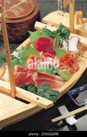 Assortiment de sashimis frais japonais dans une assiette en forme de bateau Banque D'Images