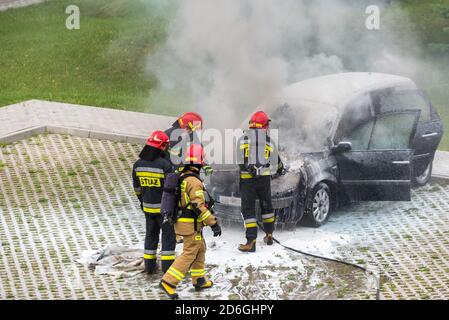 Varsovie, Pologne - 7 juillet 2020 : pompiers, mettant une voiture en feu. Des bouffées de fumée près de la voiture. Incendie de voiture dans le parking. Les pompiers ont mis le Banque D'Images