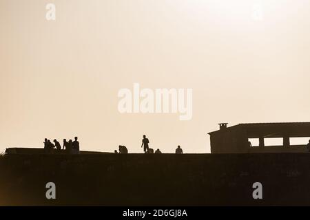 Silhouette de touristes appréciant le coucher du soleil à l'ermitage Ermida de la Lanzada à Sanxenxo, Galice, Espagne. Banque D'Images