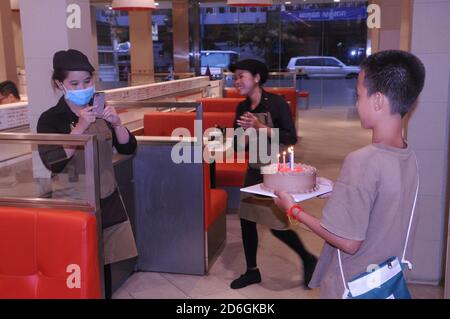 Un garçon de race mixte, cambodgien - américain, célèbre son 13e anniversaire dans un restaurant vide pendant la pandémie COVID-19. Phnom Penh, Cambodge. © Kraig Lieb Banque D'Images