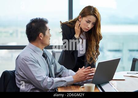 homme d'affaires et femme d'affaires asiatiques ayant une discussion dans le bureau avec ordinateur portable Banque D'Images