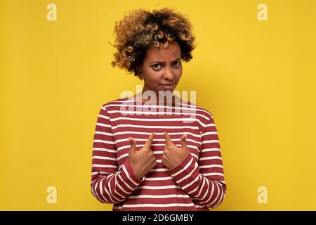 Interrogée et choquée, la femme africaine se fait remarquer en tenant le doigt sur la poitrine comme étant accusée. Banque D'Images