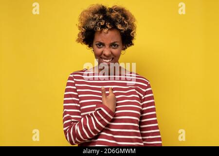 Interrogée et choquée, la femme africaine se fait remarquer en tenant le doigt sur la poitrine comme étant accusée. Banque D'Images