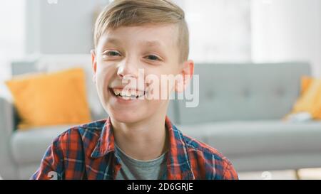 Portrait d'adorable Happy Young Boy souriant sur l'appareil photo. En arrière-plan flou salle du soleil. Banque D'Images