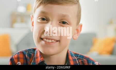 Portrait d'un adorable jeune garçon souriant à l'appareil photo. En arrière-plan flou salle du soleil. Banque D'Images