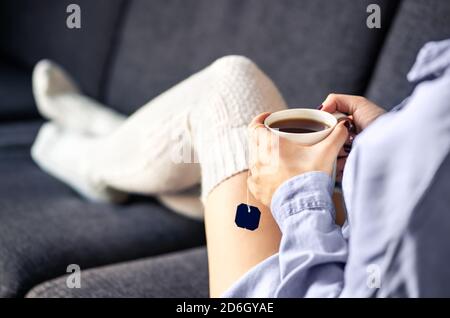 Femme en chaussettes chaudes confortables buvant une tasse de thé en hiver. Confort à la maison et matin détendu le week-end. Un style tendance pour la saison. Banque D'Images
