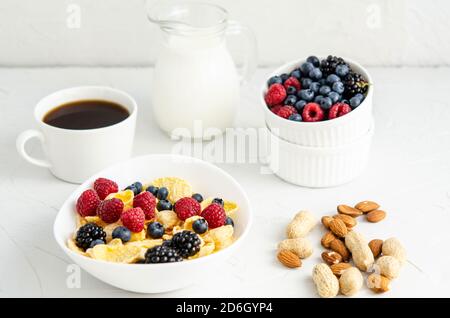 Petit déjeuner sain avec des céréales, des framboises, des mûres, des bleuets, des arachides, du lait et du café sur fond blanc. Copier l'espace, la pose à plat, la hauteur Banque D'Images