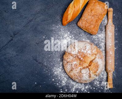 Boulangerie - divers petits pains croustillants rustiques avec pain, farine de blé, rollPIN sur fond noir. Copier l'espace, la pose à plat, placer pour le texte. Cuisson maison. Banque D'Images