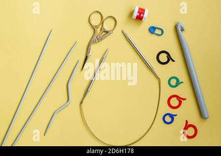 Outils de couture sur fond jaune. Épingles, marqueurs, compteur de rangées, aiguilles à tricoter et crochets, ciseaux gros plan avec espace de copie, pose à plat. À Banque D'Images