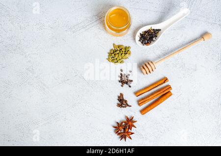 Ingrédients pour préparer une boisson traditionnelle indienne au masala. Cannelle, cardamome, anis, miel, clous de girofle, thé sec sur fond clair. Vue de dessus. Banque D'Images
