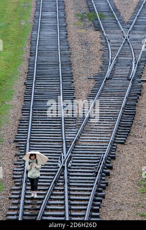 Une dame marche le long de la ligne de chemin de fer qui a amené des millions de prisonniers au musée d'État d'Auschwitz-Birkenau à Oswiecim en Pologne. Banque D'Images