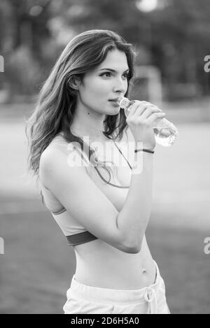 Une fille athlète boit de l'eau pendant une pause dans le sport. Photo en noir et blanc. NB Banque D'Images