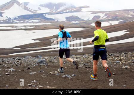 Deux athlètes coureurs courent un marathon de montagne sur le terrain enneigé de Landmannalaugar. Islande Banque D'Images
