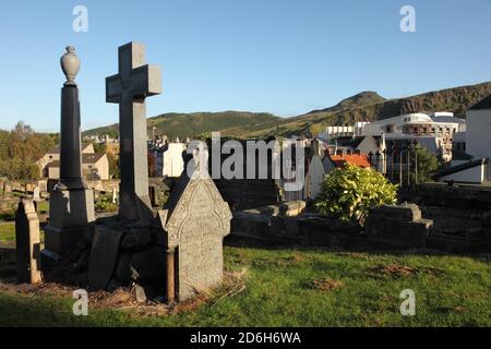 Pierres à tête dans le New Calton Burial Ground, Édimbourg, Écosse, avec le Parlement écossais, et Arthur's Seat. Banque D'Images