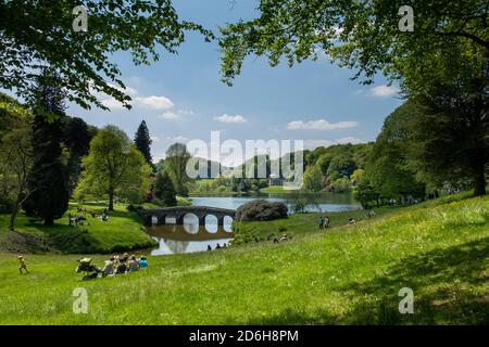 Vue sur les personnes appréciant les jardins avec le pont et Le Panthéon au milieu et loin à la Propriété National Trust à Stourhead près de M Banque D'Images