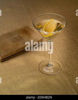 Cocktail de vodka Martini avec twist citron sur tissu doré avec vieux livre Banque D'Images