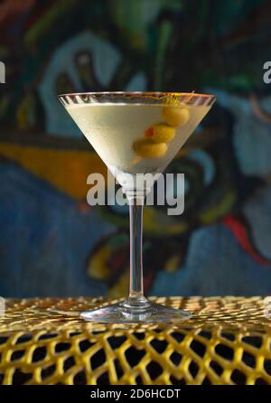 Boisson cocktail vodka martini avec des olives sur tapis d'or devant la peinture Banque D'Images