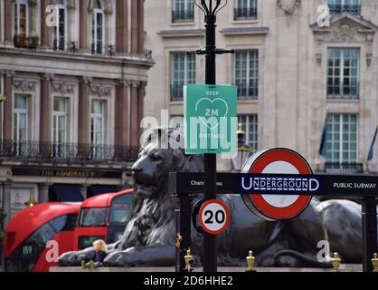Entrée du métro Charing Cross et panneau social de distance à Trafalgar Square avec l'une des statues de lion en arrière-plan, Londres, Royaume-Uni. Banque D'Images