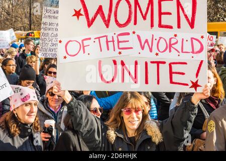 Une femme dans une foule d'autres personnes tenant un panneau, « Women of the World Unite », à la marche des femmes de Boston. Banque D'Images