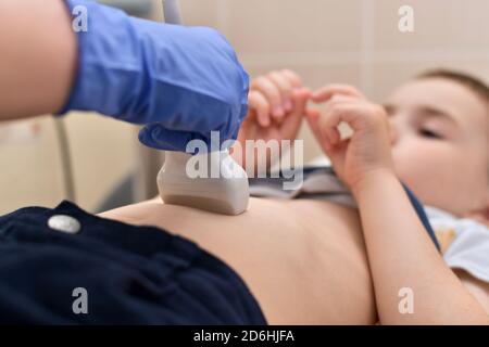 L'enfant passe les doigts sur l'examen échographique. Diagnostic médical par un capteur, main dans un gant. Banque D'Images