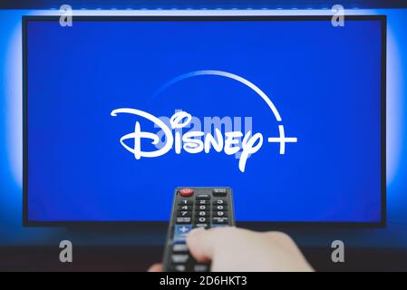 Wroclaw, Pologne - OCT 13, 2020: Man détient une télécommande. Logo Disney+ sur l'écran du téléviseur en arrière-plan. Disney+ est un nouveau service de streaming vidéo en ligne Banque D'Images
