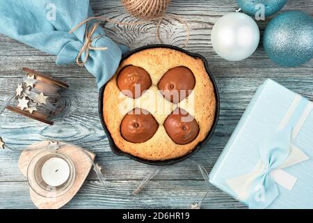 Table festive avec gâteau aux poires, bougies et boîte cadeau sur fond de bois. Banque D'Images