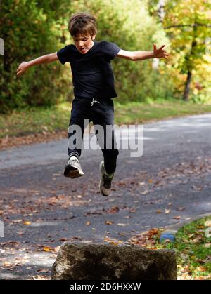 Un garçon sportif de 8 ans sautant haut dans le air Banque D'Images