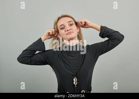 Portrait d'oreilles humaines amusantes et attrayantes imitant le singe et regardant l'appareil photo. Oreille élongante à l'intérieur. Se tirant. Jeune femme attirante, vêtue de chandail noir avec des yeux verts Banque D'Images