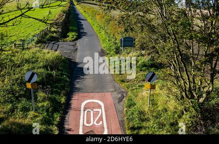 Route de campagne avec limite de vitesse de 20 mph peint sur tarmac le jour ensoleillé, East Lothian, Écosse, Royaume-Uni vu de Pencaitland chemin de fer Banque D'Images