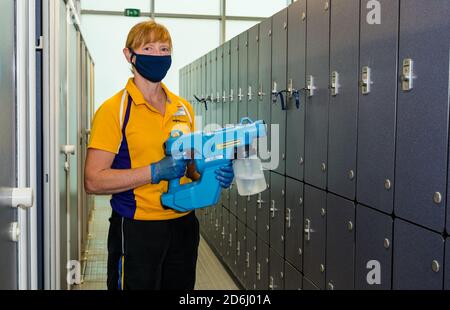 Personnel féminin portant des casiers de nettoyage de masque facial avec pulvérisateur d'hygiène de brouillard à Covid-19 pandémie, centre sportif de North Berwick, East Lothian, Écosse Banque D'Images