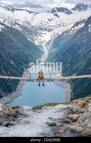 Randonneur, femme sur le pont suspendu à Olpererhuette, réservoir Schlegeis, réservoir Schlegeis, Alpes de Zillertal, glacier Schlegeiskees, Zillertal Banque D'Images