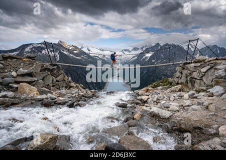 Randonneur, femme sur le pont suspendu à Olpererhuette, réservoir Schlegeis, réservoir Schlegeis, Alpes de Zillertal, glacier Schlegeiskees, Zillertal Banque D'Images