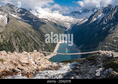 Randonneur, femme sur le pont suspendu à Olpererhuette, réservoir Schlegeis, réservoir Schlegeis, Alpes de Zillertal, glacier Schlegeiskees, Zillertal Banque D'Images