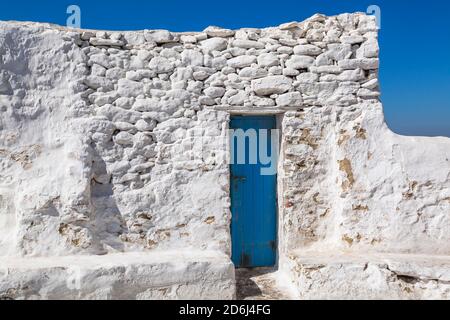 Mur en pierre peinte en blanc et étroite porte d'entrée peinte en bleu, ville de Mykonos, île de Mykonos, Grèce Banque D'Images