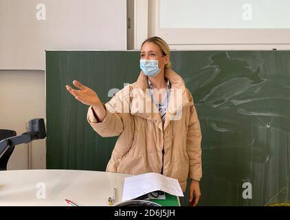 Professeur avec une veste d'hiver épaisse et un masque facial dans l'enseignement en salle de classe, les gestes, la crise corona, Stuttgart, Bade-Wurtemberg, Allemagne Banque D'Images