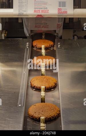 Gros biscuits sur le convoyeur d'une usine commerciale machine à emballer pour former des biscuits emballés individuellement Banque D'Images