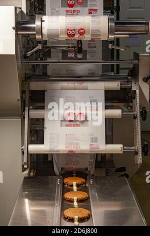 Gros biscuits sur le convoyeur d'une usine commerciale machine à emballer pour former des biscuits emballés individuellement Banque D'Images