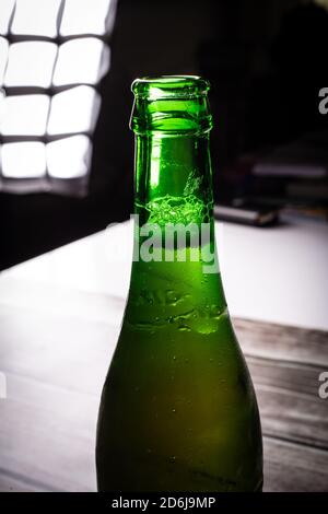 la bouteille de bière blonde de bière verte ouverte ferme encore isolée sur fond en bois Banque D'Images