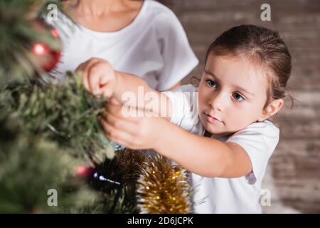 Foyer sélectif de fille debout près de la mère et la décoration de noël pin Banque D'Images