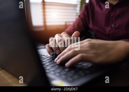 Jeune homme noir développeur assis dans un restaurant pizza, boire du café ou du thé et travailler avec un ordinateur portable. Banque D'Images